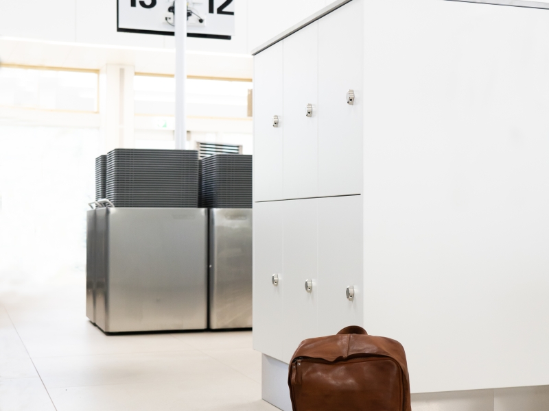 Hochwertiger, schöner und geräumiger Spind-Verbau für Flughafenpersonal im Bereich der Sicherheitskontrolle nach optischen Kundenwünschen ausgeführt: Materialkombination aus Edelstahl und weißem Dekorholz