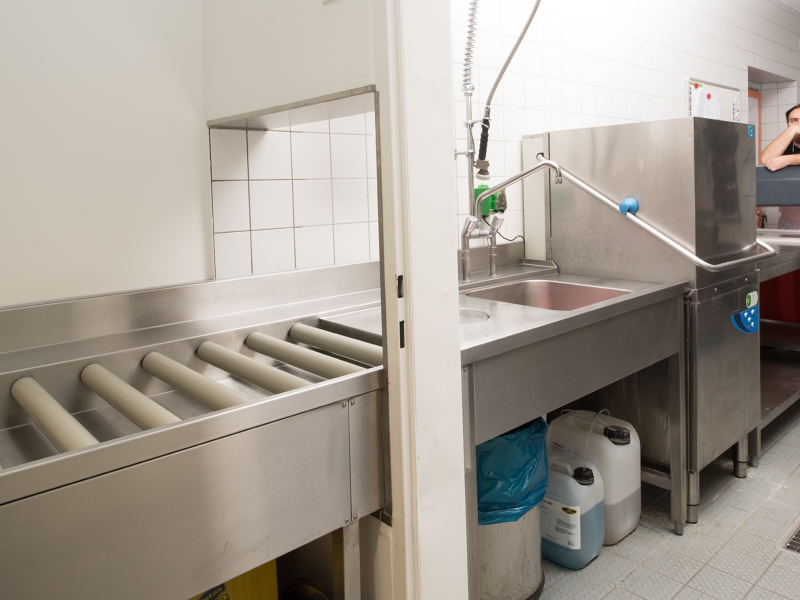 Zulauftisch für Haubenspüler in Spezialausführung (Rollen für leichte Fortbewegung der Waschkörbe; Durchführung durch Mauerwerk)